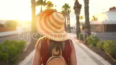 <strong>摄影</strong>女游客戴着一顶黄色的大帽子，在夕阳下美丽的<strong>热带</strong>风景中用相机拍照